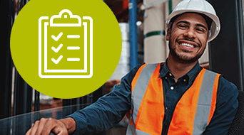 A smiling person wearing an orange safety vest and white hard hat stands indoors at a small-business-shipping-hub. To the left, a green circle with a white checklist icon. The background features industrial elements, highlighting the efficient operations underway.