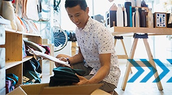 Shop owner with clipboard processing new merchandise