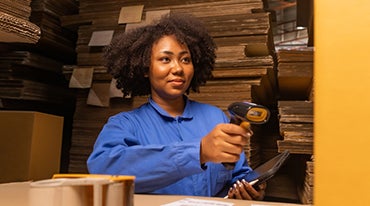 People working in storage, taking parcel and scanning barcode, putting box on shelf. Female business person at workplace in warehouse, concept of delivering and logistics. Businesswoman owner.