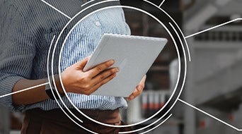 A person in a blue striped shirt holds a tablet amidst digital circular overlay graphics, evoking a tech-forward ambiance. This scene captures the essence of a small-business-shipping-hub, seamlessly blending innovation with efficiency in a futuristic backdrop.