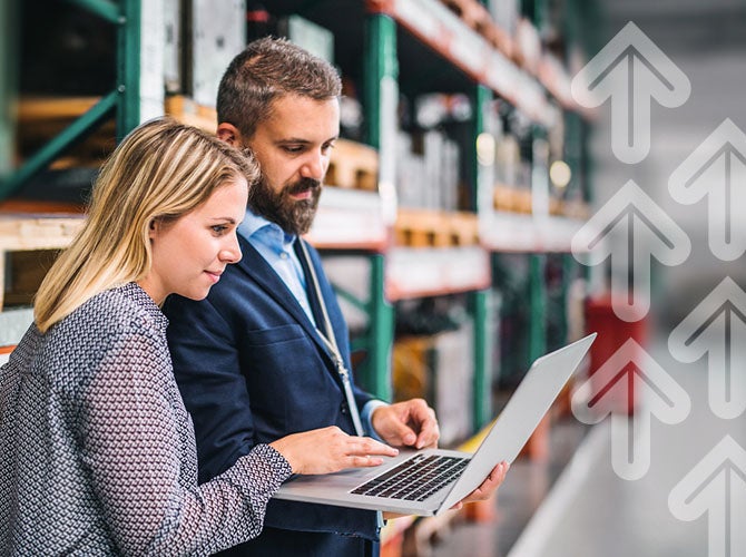 A portrait of a mature industrial man and woman engineer with laptop in a factory, working.